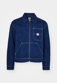 Chaqueta de mezclilla azul oscuro con cremallera frontal, dos bolsillos delanteros, costuras en blanco en contraste y un pequeño parche con el logo de Lee en el bolsillo del pecho.