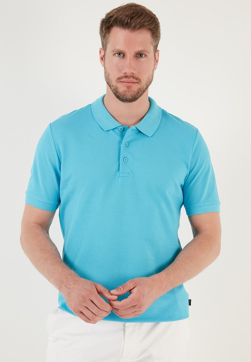 Polo de color turquesa con mangas cortas, tapeta de tres botones y un acabado texturizado. Diseño liso sin patrones o acentos visibles.