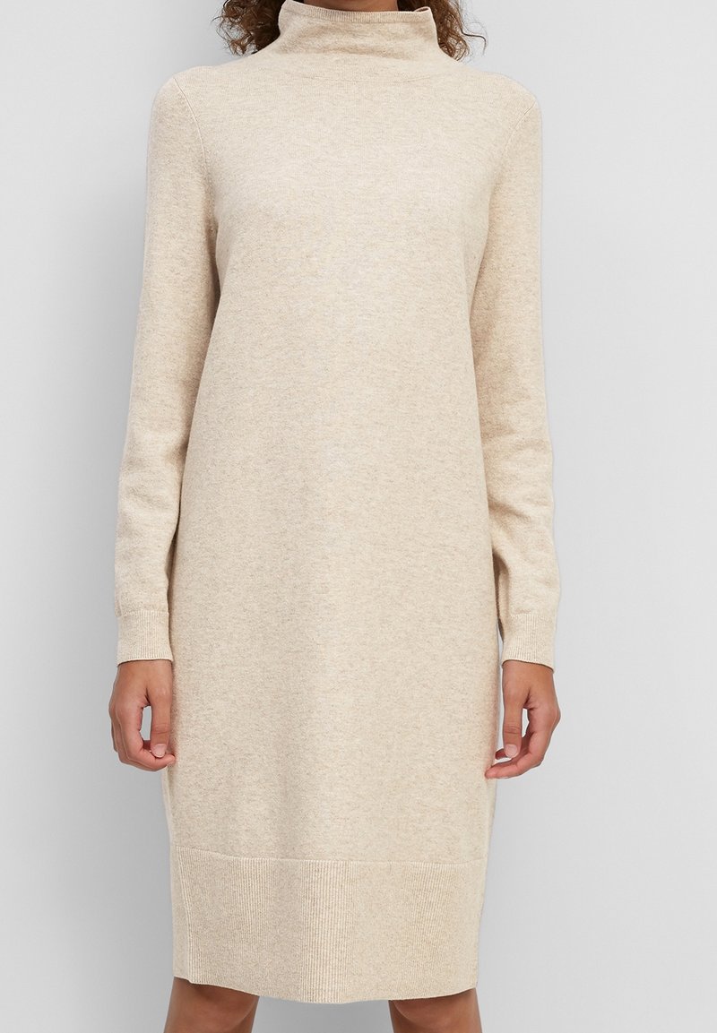 Beige Rollkragenkleid aus weichem Strickstoff. Verfügt über lange Ärmel, gerippte Bündchen und eine gerade Silhouette. Glatte Textur.