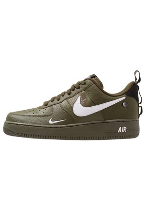 Niskie buty sportowe w kolorze oliwkowej zieleni z białymi znakami Nike, teksturowaną skórzaną cholewką, pętelką na pięcie i oznaczeniem "AIR" na podeszwie środkowej.
