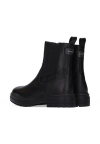 Zwarte enkellaarsjes met een textuurleer afwerking, elastische zijkanten en aantrek-lussen. Stevige zwarte rubberen zolen met subtiele merkaanduidingen.