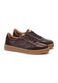 Sneaker in pelle marrone con dettagli perforati, accenti color nocciola e un motivo discreto sulla suola. Dotate di chiusura con lacci e collo imbottito.