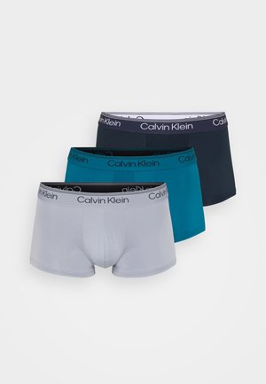 Kolme paria Calvin Kleinin bokserialushousuja harmaana, turkoosina ja laivastonsinisenä, joissa on joustavat vyötärönauhat brändin logolla. Sileä kangaspinta.