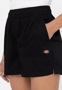 Čierne šortky z bavlny s elastickým pásom. Obsahujú bočné vrecká a malú nášivku s logom Dickies. Rovný strih so bočnými rozparokmi.