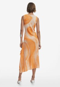Abito arancione con un motivo vorticoso, realizzato in un tessuto leggero. Presenta un design senza maniche e un orlo asimmetrico.