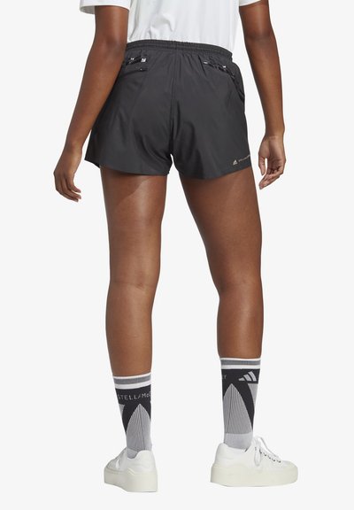 Pantaloni sportivi neri con vita elastica, due tasche posteriori e materiale leggero. Abbinati a calzini con motivo e sneakers bianche.