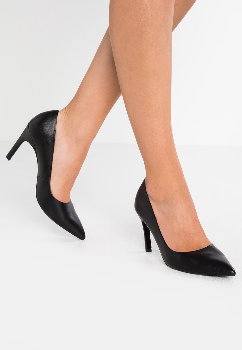 Escarpins noirs à talons hauts en cuir lisse, avec un bout pointu, un design élégant et une découpe incurvée le long de la coupure du cou-de-pied.