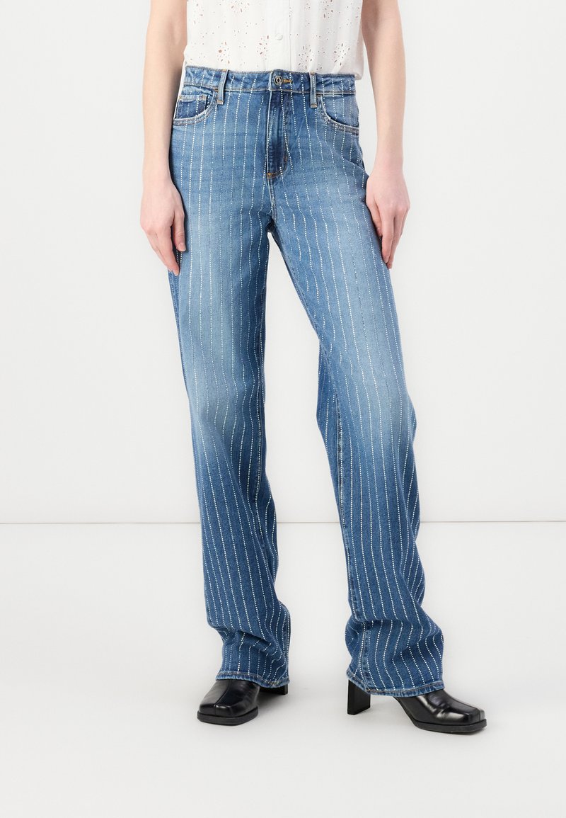 Jean en denim bleu clair avec des rayures verticales blanches, un design classique à cinq poches et une silhouette légèrement évasée.