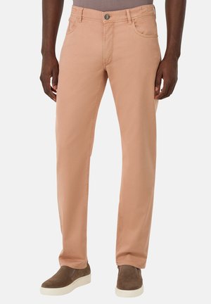 Pantalons en coton rose clair avec une coupe droite, poches avant et fermeture à bouton sur le devant. Portés avec des chaussures brunes à enfiler.