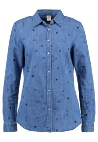 Denim blouse met lange mouwen, lichtblauwe kleur, voorzien van kleine geborduurde hartjes in marineblauw, wit en lichtblauw. Knopen aan de voorkant, design met kraag.