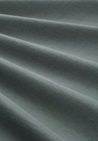 Textúrovaná tkanina v tmavosivej farbe s jemným leskom, s mäkkými, splývavými závesmi a hladkým povrchom s tkaným vzorom.