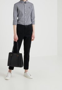 Musta-valkoinen ruudullinen paita, vartalonmyötäiset mustat housut, valkoiset tennarit ja musta nahkainen olkalaukku kultaisilla yksityiskohdilla.