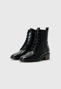 Black leather ankle boots with a lace-up design, rounded toe, and low block heel. Features a pull tab at the back for easy wear.