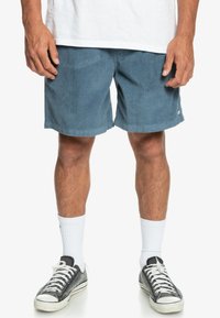 Blå ribbade shorts med regular fit, med en nederkant ovanför knäet och en liten logotypdetalj på sidan. Bärs med sneakers och vita strumpor.