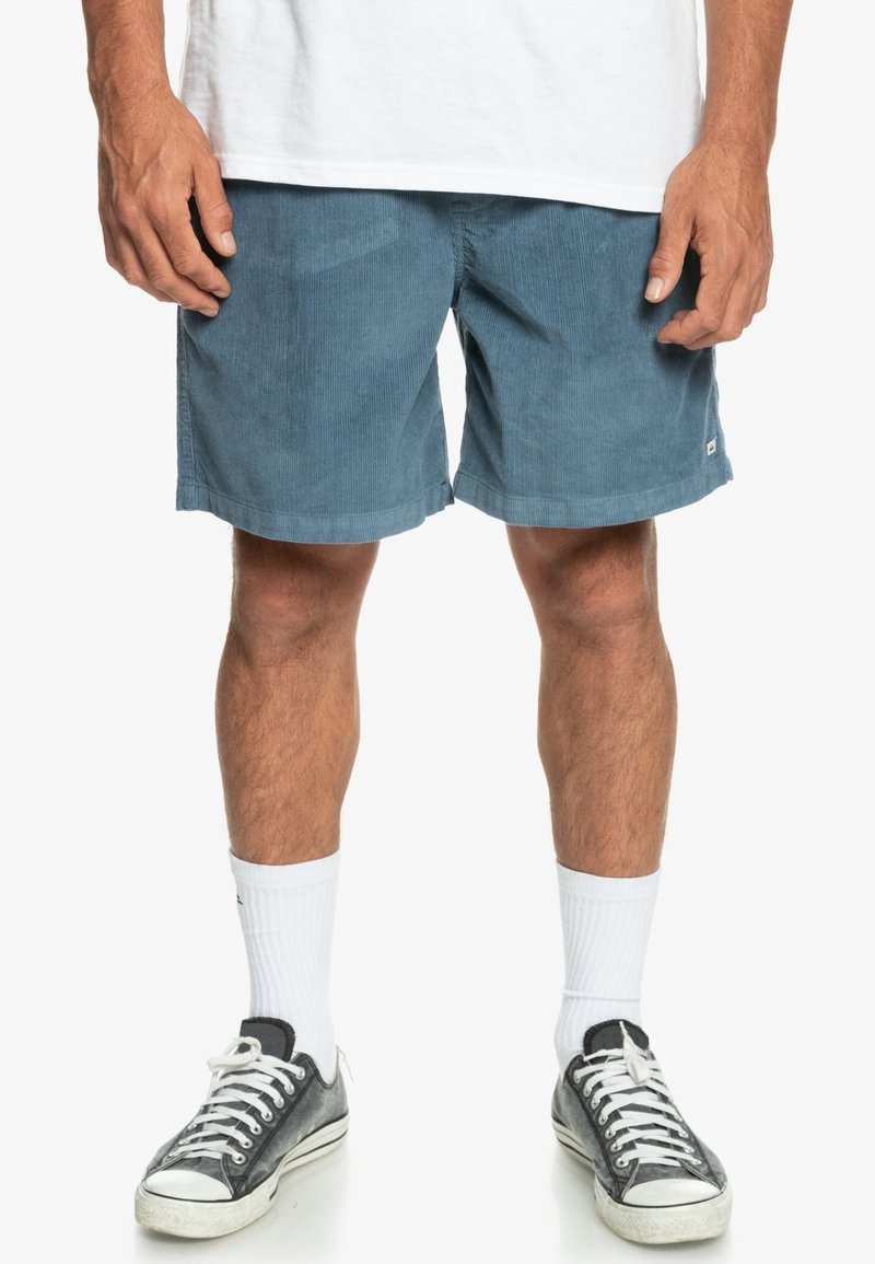 Blå ribbade shorts med regular fit, med en nederkant ovanför knäet och en liten logotypdetalj på sidan. Bärs med sneakers och vita strumpor.