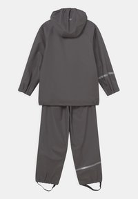 Szary wodoodporny kombinezon przeciwdeszczowy z kapturem. Posiada długie rękawy i spodnie, wyposażony jest w odblaskowe akcenty dla zwiększenia widoczności, gładka faktura.