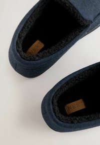 Marine blauwe instappers gemaakt van gestructureerde stof met een zachte fleece voering en een zwarte rubberen zool. Voorzien van een leren label met "NEXT."