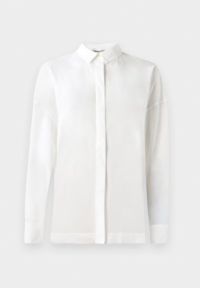 Camicia bianca a maniche lunghe con colletto bottonato, tessuto liscio, taglio dritto e patta nascosta. Tessuto morbido e leggero senza fantasie.
