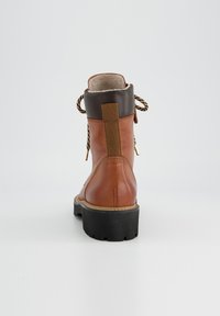 Bottines en cuir brun avec bout rond, dessus en cuir texturé brun et lacets à motif. Elles disposent d'un col rembourré et d'une semelle en caoutchouc épaisse.