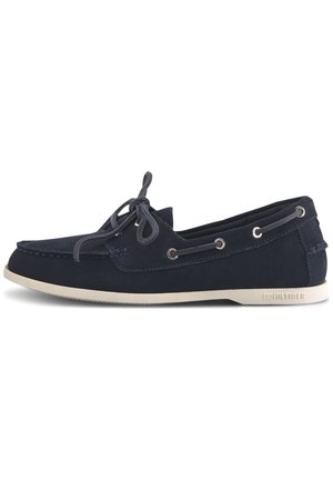 Scarpa da barca in camoscio blu navy con suola in gomma bianca, superficie texturizzata, design con lacci e occhielli in metallo per un dettaglio extra.