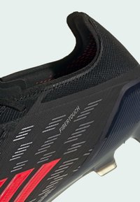 Μαύρο αθλητικό παπούτσι με υλικό FIBERTOUCH, υφή επιφάνειας, κόκκινες λεπτομέρειες και κομψό σχεδιασμό με χαμηλό προφίλ και στρατηγικά τοποθετημένα εξαρτήματα.