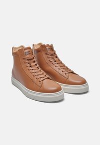 Sneakers high-top in pelle marrone con finitura testurizzata, suole in gomma bianca e laccio laterale. Accentuati da un colletto beige e branding all'interno.