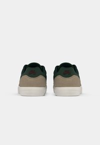 Sneakers with a dark green upper and tan suede accents, featuring a white sole. Includes small red Nike logo on the back.