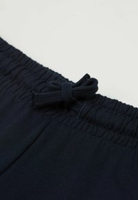 Námořnická modrá elastická páska v pase s nařasenou strukturou a tkanou šňůrkou na stažení. Hladká, pružná látka bez viditelných vzorů nebo dekorací.