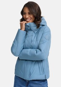 Helle blaue Daunenjacke mit hohem Kragen, Reißverschluss und Seitentaschen. Glatte Textur mit gesteppter Naht und Logo am Ärmel.