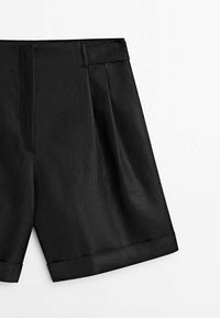 Shorts noirs sur mesure avec ourlets retroussés, fermeture éclair frontale cachée et passants pour ceinture sur fond blanc.