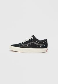 Tenisii negri din pânză cu studuri argintii pe laturi, șireturile albe și o talpă din cauciuc crem. Design clasic de tip low-top, cu cusături contrastante.
