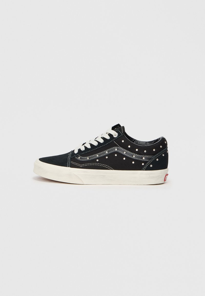 Tenisii negri din pânză cu studuri argintii pe laturi, șireturile albe și o talpă din cauciuc crem. Design clasic de tip low-top, cu cusături contrastante.