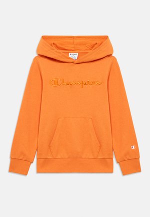 Oranžinis megztinis su gaubtu ir priekiu kišene. Ant jo siuvinėtas „Champion“ logotipas. Minkšta medžiaga su ribotais rankogaliais ir apačia.