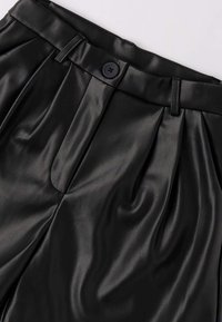 Pantaloni in ecopelle nera con una consistenza liscia, dotati di pieghe, chiusura con bottone e passanti per cintura in vita.