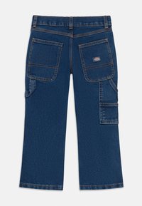 Dunkelblaue Denim-Arbeitshosen mit doppelten Gesäßtaschen, Werkzeugschlaufen an den Seiten, orangefarbener Naht und einem kleinen Markenpatch auf der rechten Tasche.