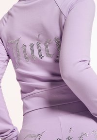 Lavender Trainingsanzug mit einer figurschmeichelnden Passform und langen Ärmeln, verziert mit silbernen Strasssteinen, die auf dem Rücken "Juicy" buchstabieren.