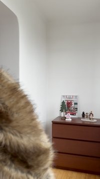 Brun träbyrå med tre lådor, med ett litet grönt träd, en vit husdekoration och ett inramat foto på toppen.