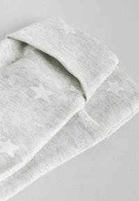 Grauer Stoff mit einem dezenten Sternenmuster, der eine weiche Textur und eine umgerollte Kante aufweist. Das Material wirkt leicht und atmungsaktiv.