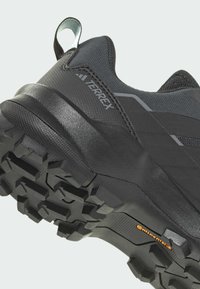 Scarpa da trekking nera Terrex con upper sintetico testurizzato, suola in gomma resistente, modello di battistrada aggressivo e accenti riflettenti.