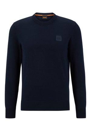 Suéter de punto azul marino con cuello redondo, puños y dobladillo acanalados. Presenta un parche de logo texturizado en el pecho y un acento naranja en el cuello.