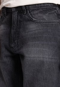 Černé džíny z denimu s hladkou texturou, jemným vyblednutím a klasickým designem pěti kapes. Těžký materiál s prošívanými švy.
