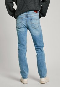 Ljusblå denimjeans med rak passform, med midjehöjd och subtila blekningar. Inkluderar två bakfickor med sömnadsdetaljer.