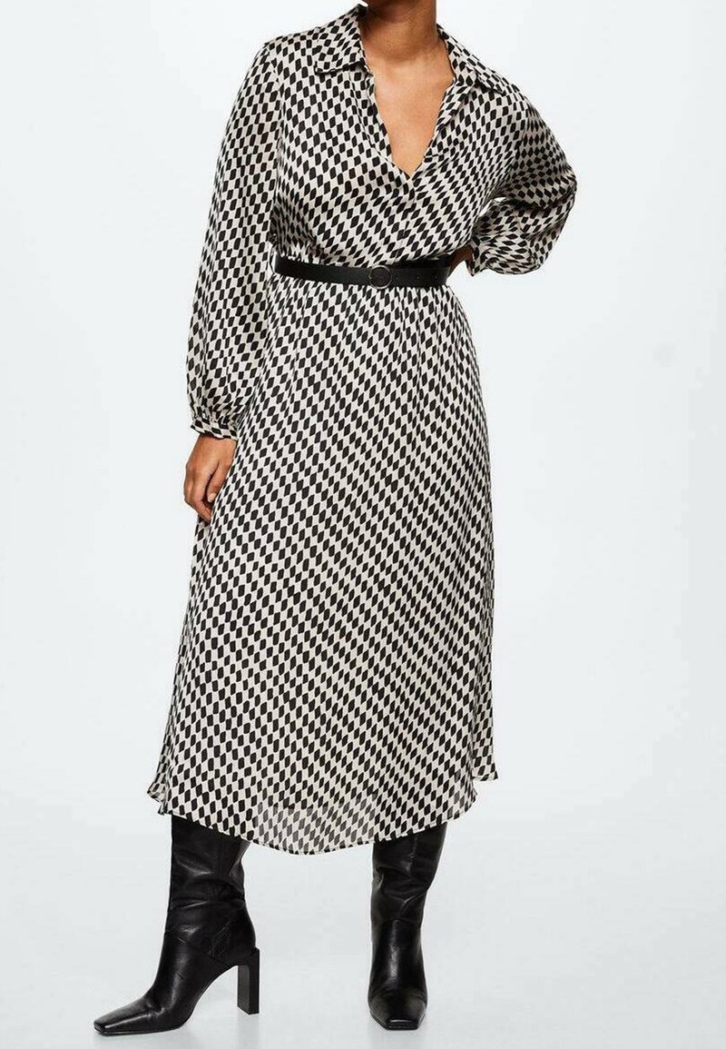 Vestido a rayas en blanco y negro con cuello tipo solapa, mangas largas, cintura ceñida y falda fluida, combinado con botas negras hasta la rodilla.
