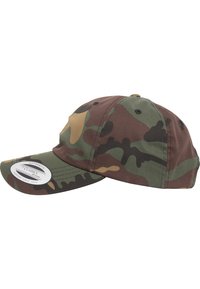 Camo pet met een gebogen rand, gemaakt van katoen, met een mix van groen, bruin en zandkleurige tinten, en stikdetails. Etiket zichtbaar op de rand.