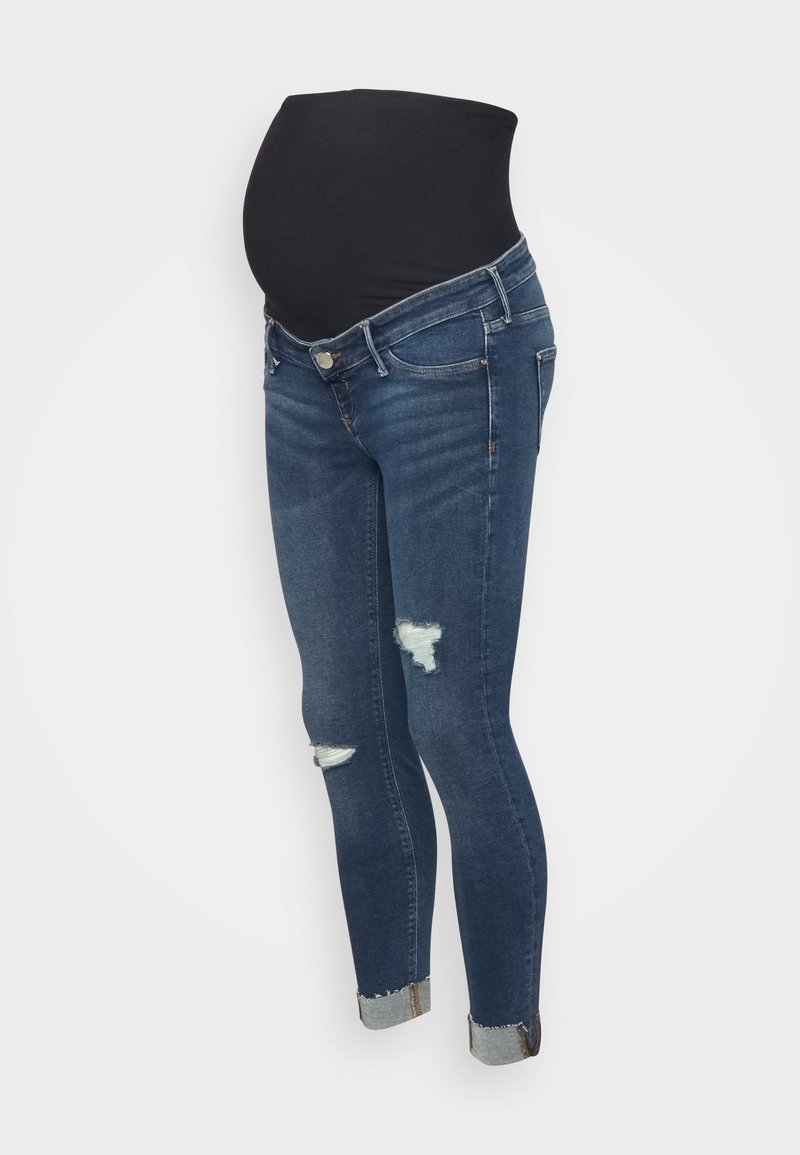 Jeans de maternidad en denim azul oscuro con una cinturilla elástica negra, de corte slim, que presentan detalles desgastados y los dobladillos enrollados.