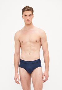 Caleçons pour hommes bleu marine en tissu doux, dotés d'une large ceinture élastique avec logo et d'une coupe ajustée, conçus pour le confort et le soutien.