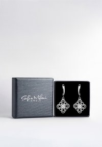 Silberne florale Tropfenohrringe in einer mit schwarzem Samt ausgekleideten Box, die über filigrane Ausstanzungen und Hakenbefestigungen verfügen. Die Box hat eine strukturierte silberne Oberfläche.