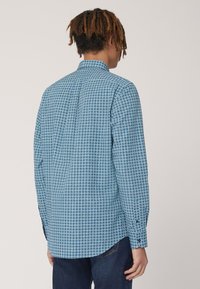 Camicia a maniche lunghe di un blu brillante con un motivo geometrico, dotata di colletto classico, polsini con bottone e orlo dritto.
