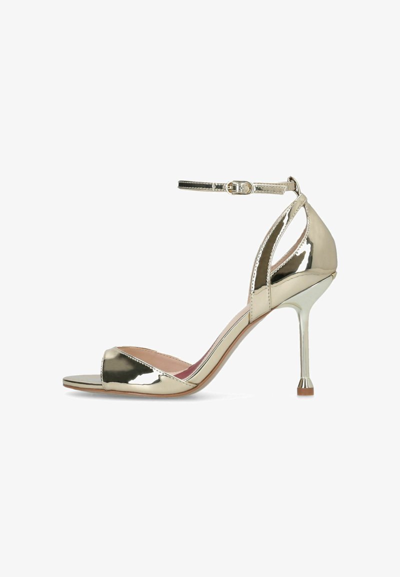 Sandalia de tacón stiletto metálica dorada brillante con correa en el tobillo y puntera abierta, acabado liso y tacón delgado de altura media.