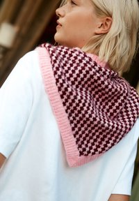 Châle triangulaire tricoté en bordeaux et rose ; présente un motif à carreaux avec une texture douce et duveteuse et une bordure rose unie. Haut blanc en dessous.